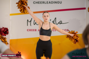 cheerleaderka z pomponami w pozycji arm motion diagonal