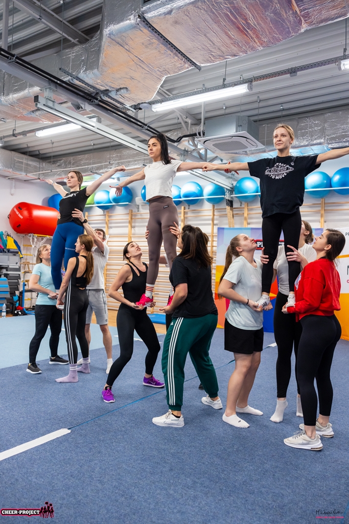 trzy stunty grupowe uczestników szkolenia cheer acro basic tworzące piramidę na poziomie prep